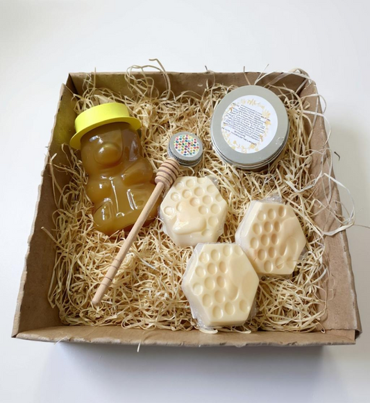 Box of honey and honeycomb-shaped soaps on a white background